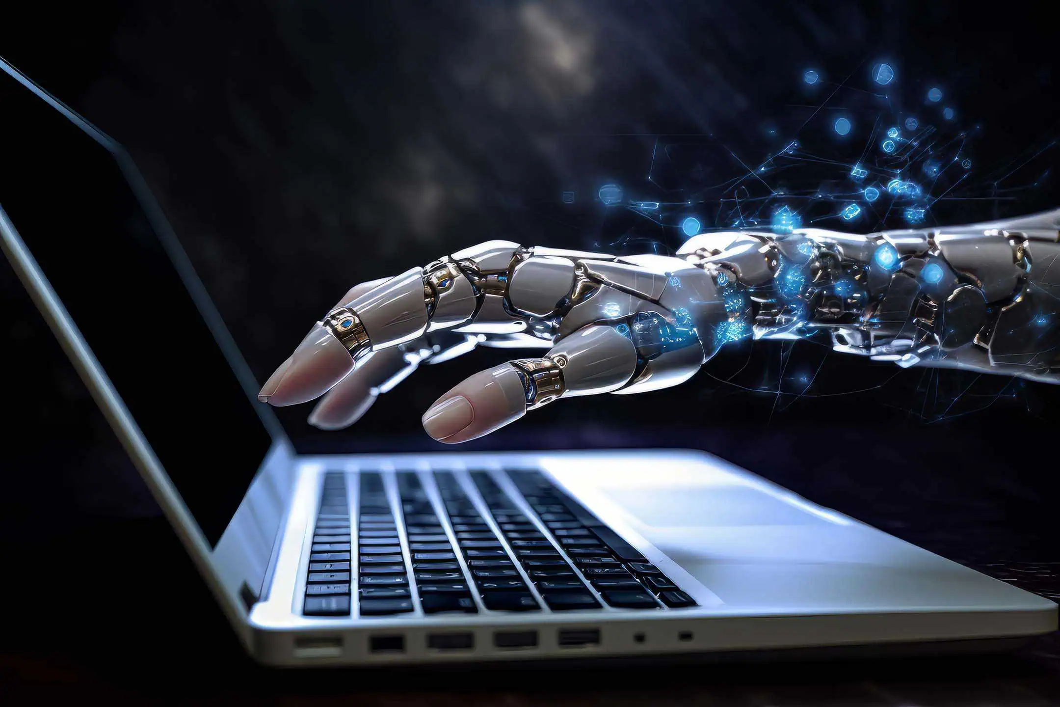 A robot's hand above a computer keyboard, ready to type