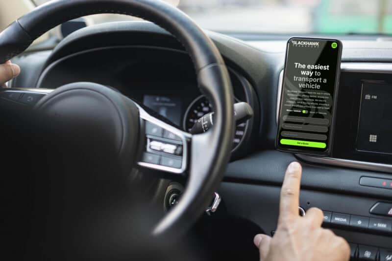 A smartphone attached to a car dashboard displaying the Blackhawk Transport quote form