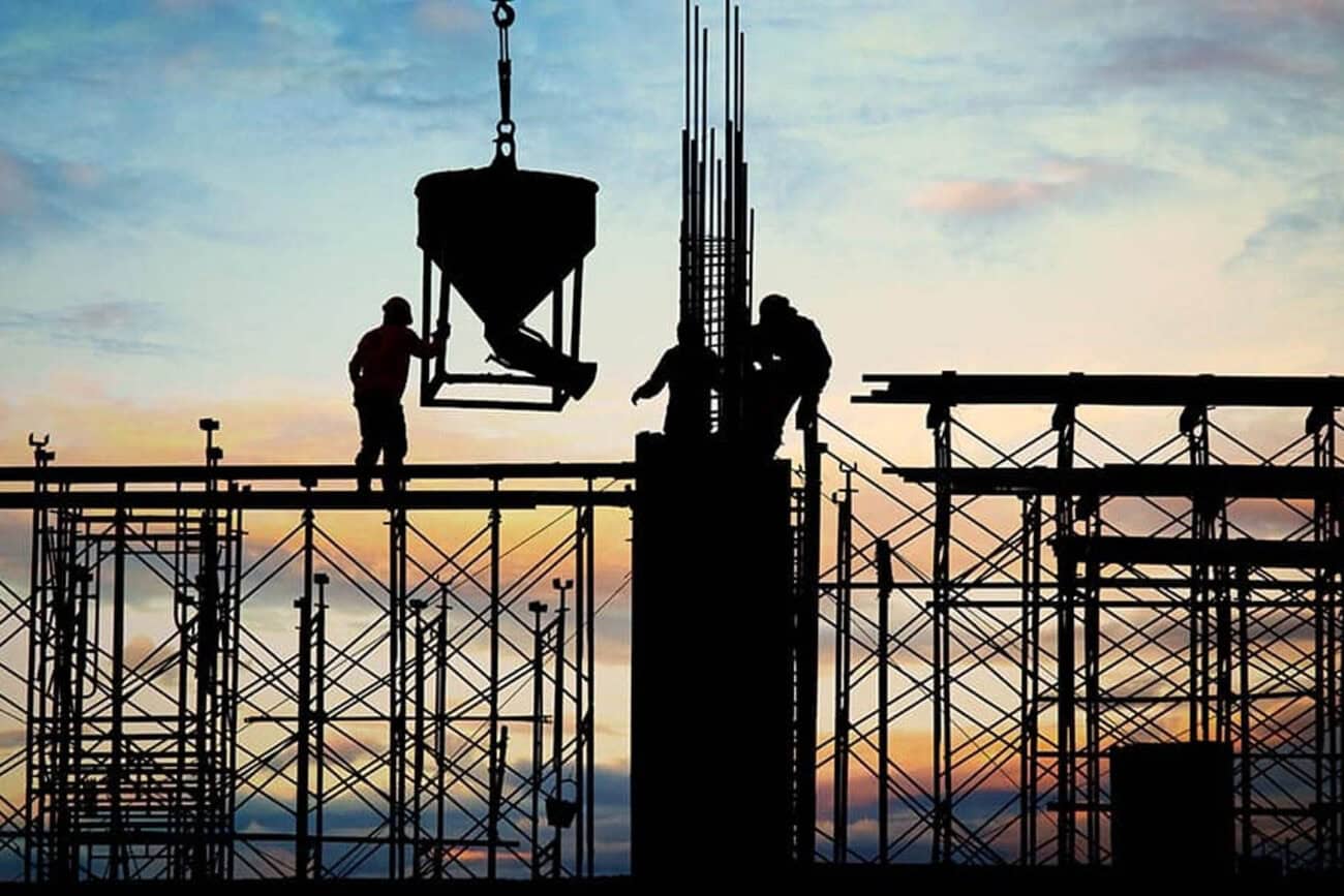 A silhouette of construction workers against a dusk sky