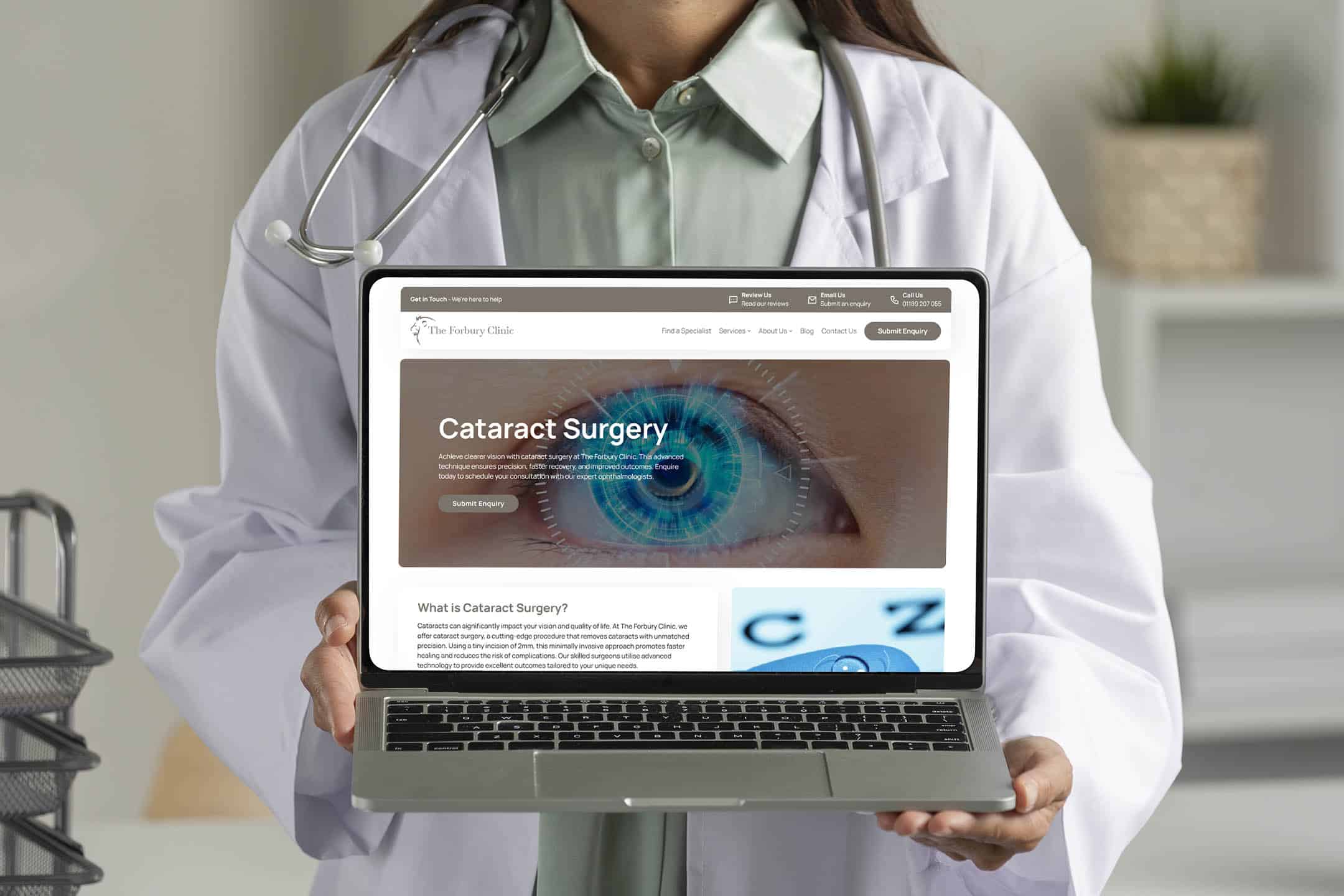 A doctor holding a laptop that shows the Cataract Surgery page from The Forbury Clinic website