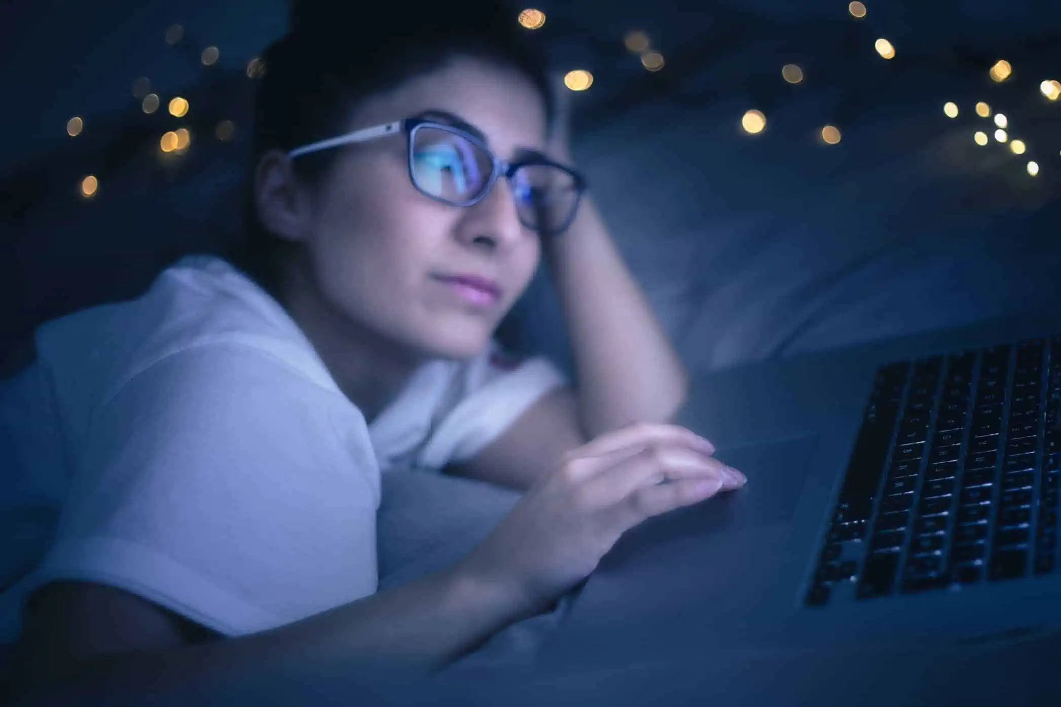 A woman laying in bed at night using her laptop