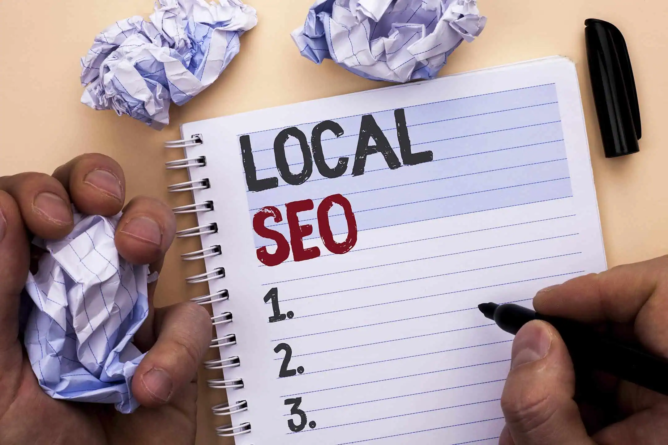 A man writing the words Local SEO in a notebook, with an empty numbered list