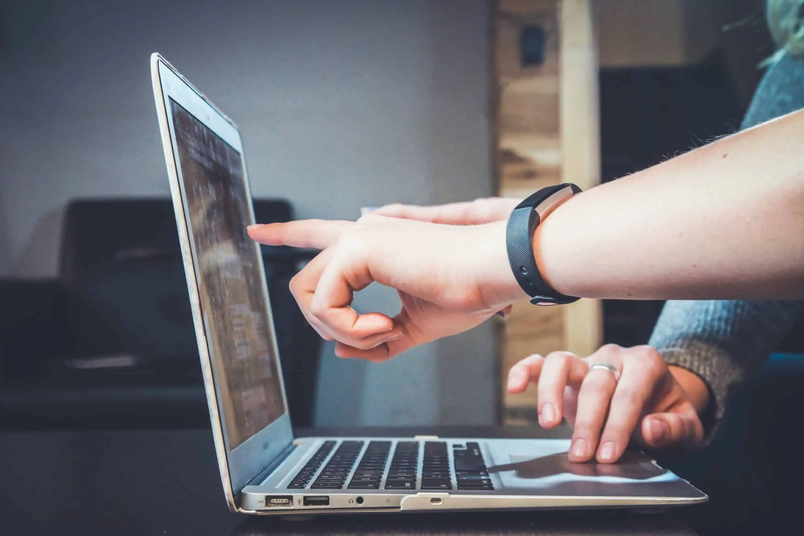 Two people pointing at a laptop screen