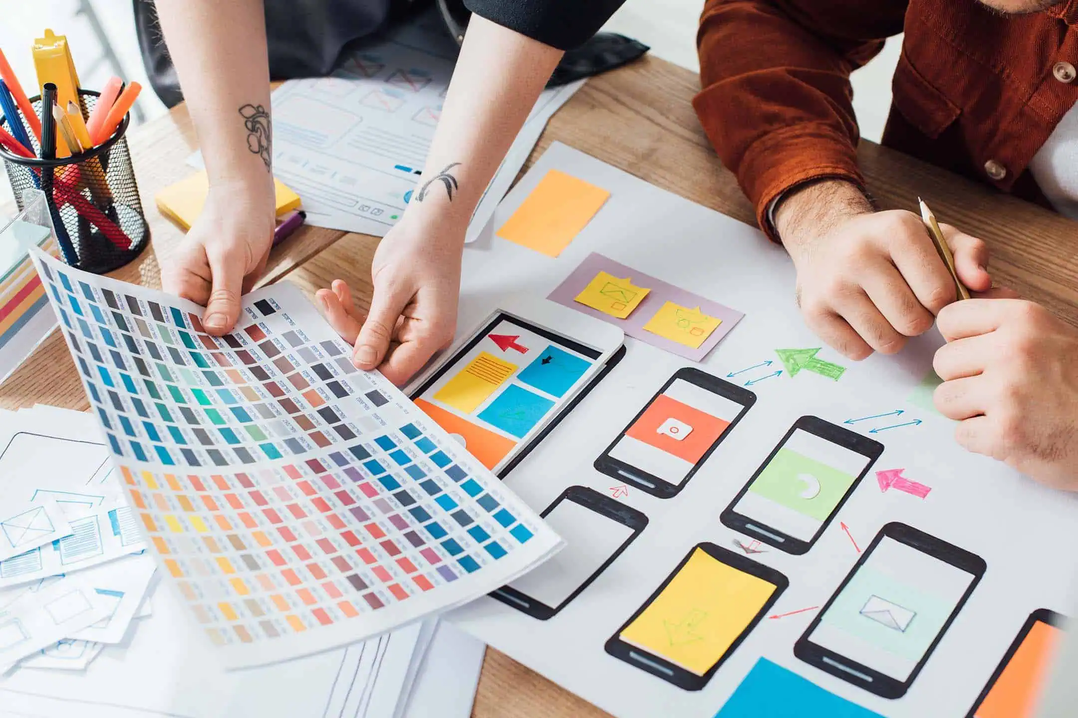 Designers sitting at a desk looking at colour swatches while designing a mobile interface