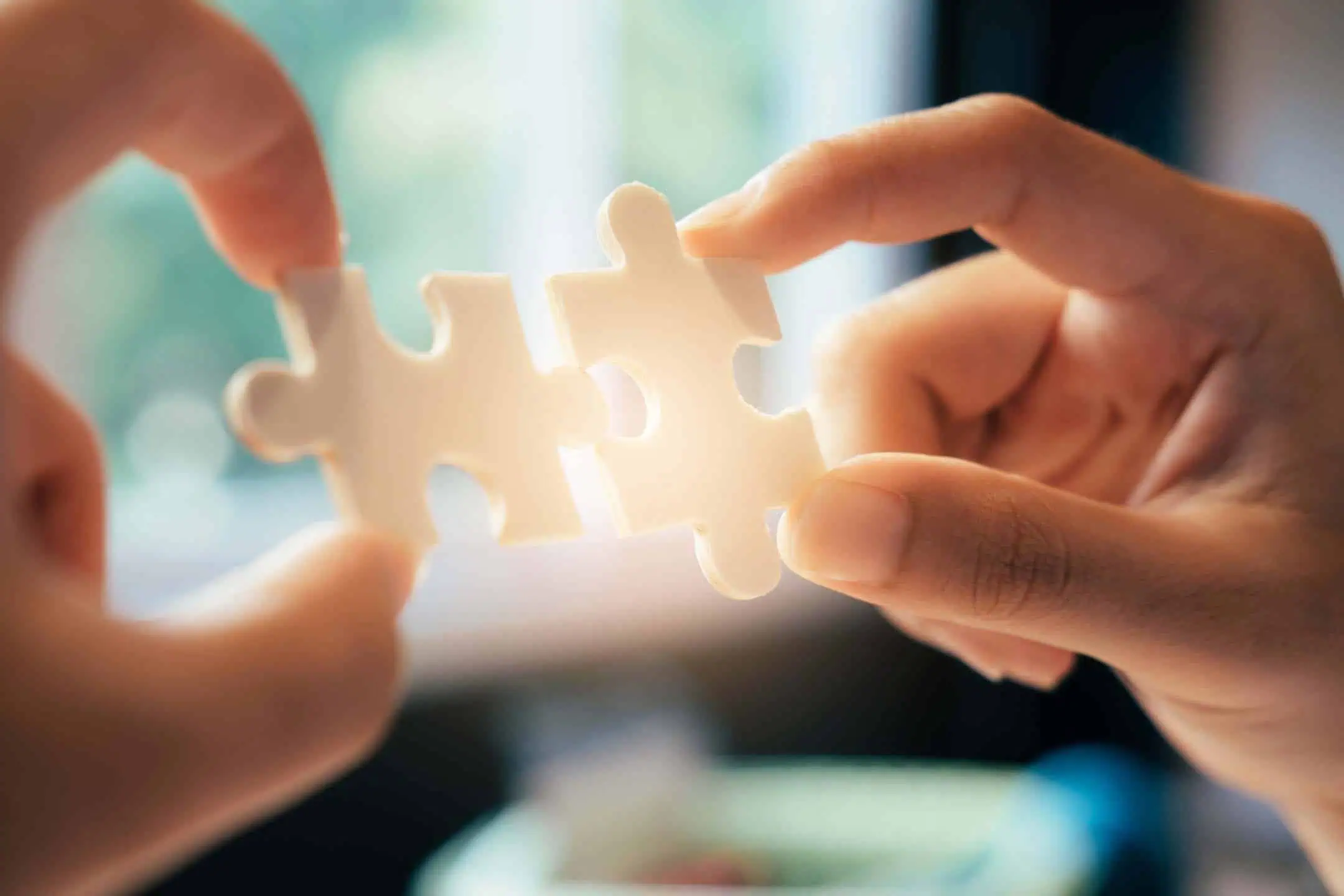 A woman holding up two jigsaw pieces, as she connects them together