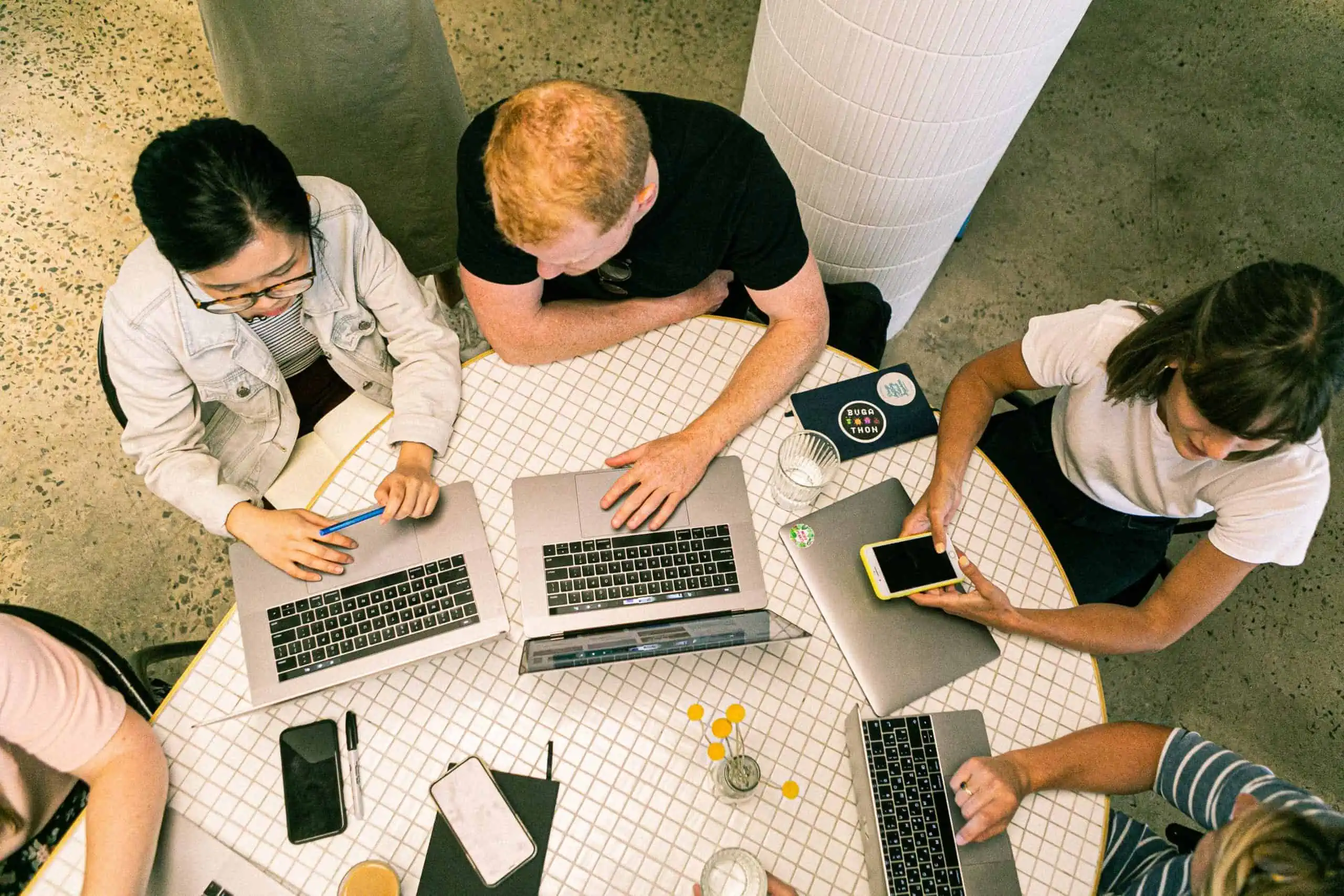 A top-down shot of a team meeting at a table filled with laptops