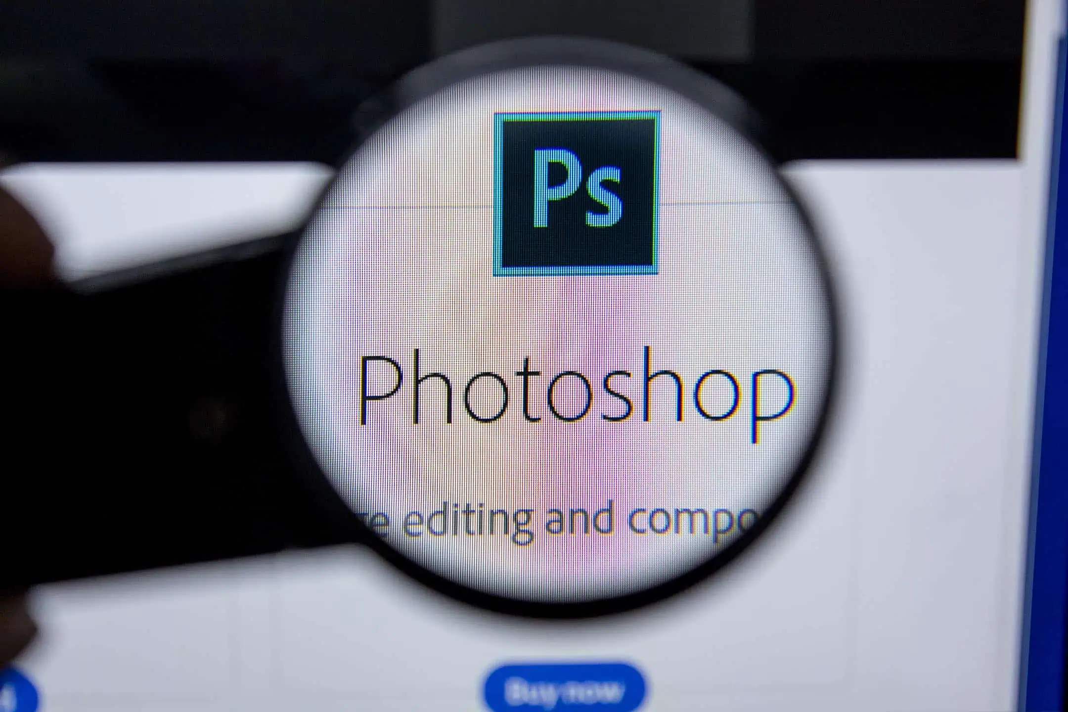 Photoshop Logo on a laptop screen shown under a magnifying glass