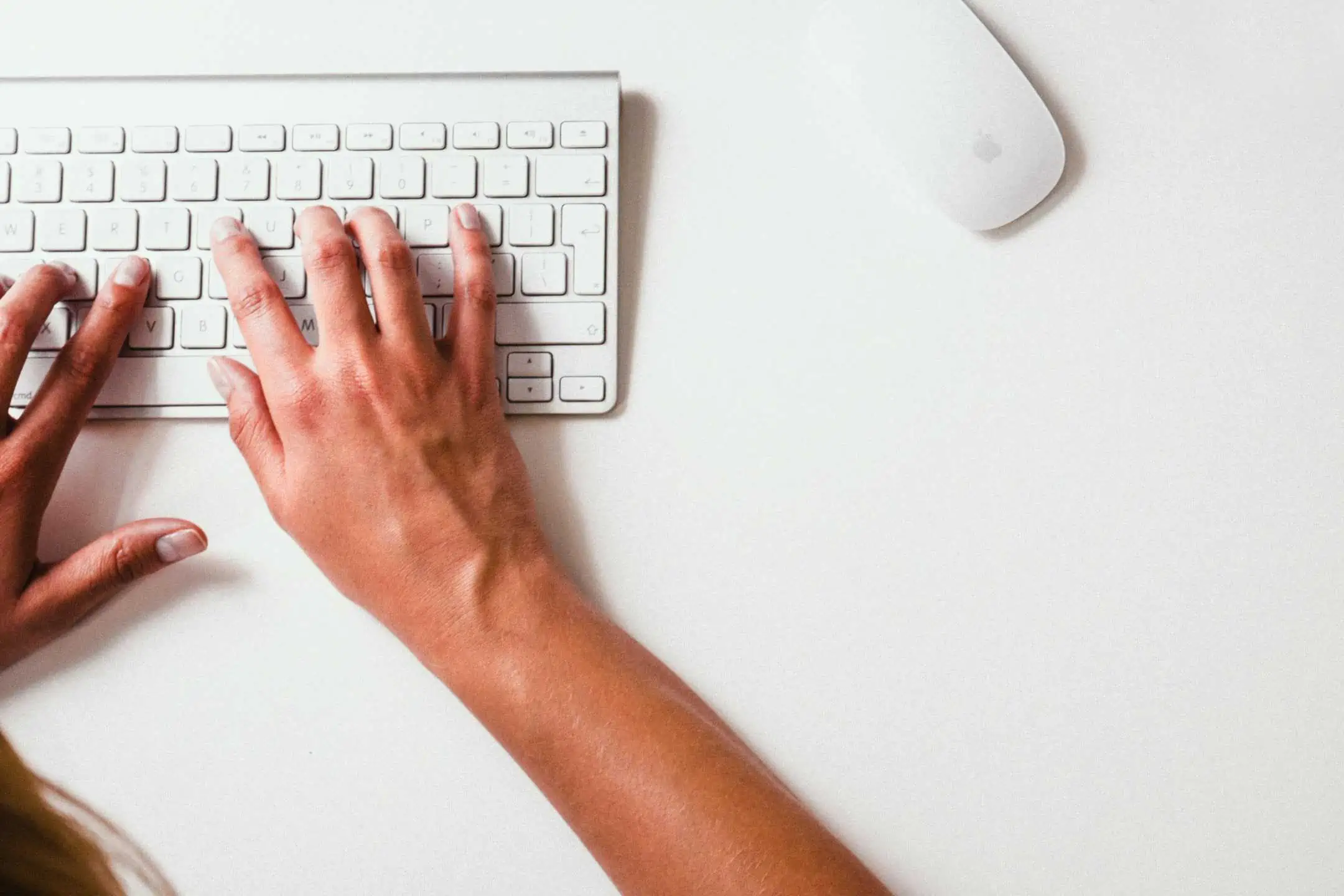 A woman typing on an Apple keyboard