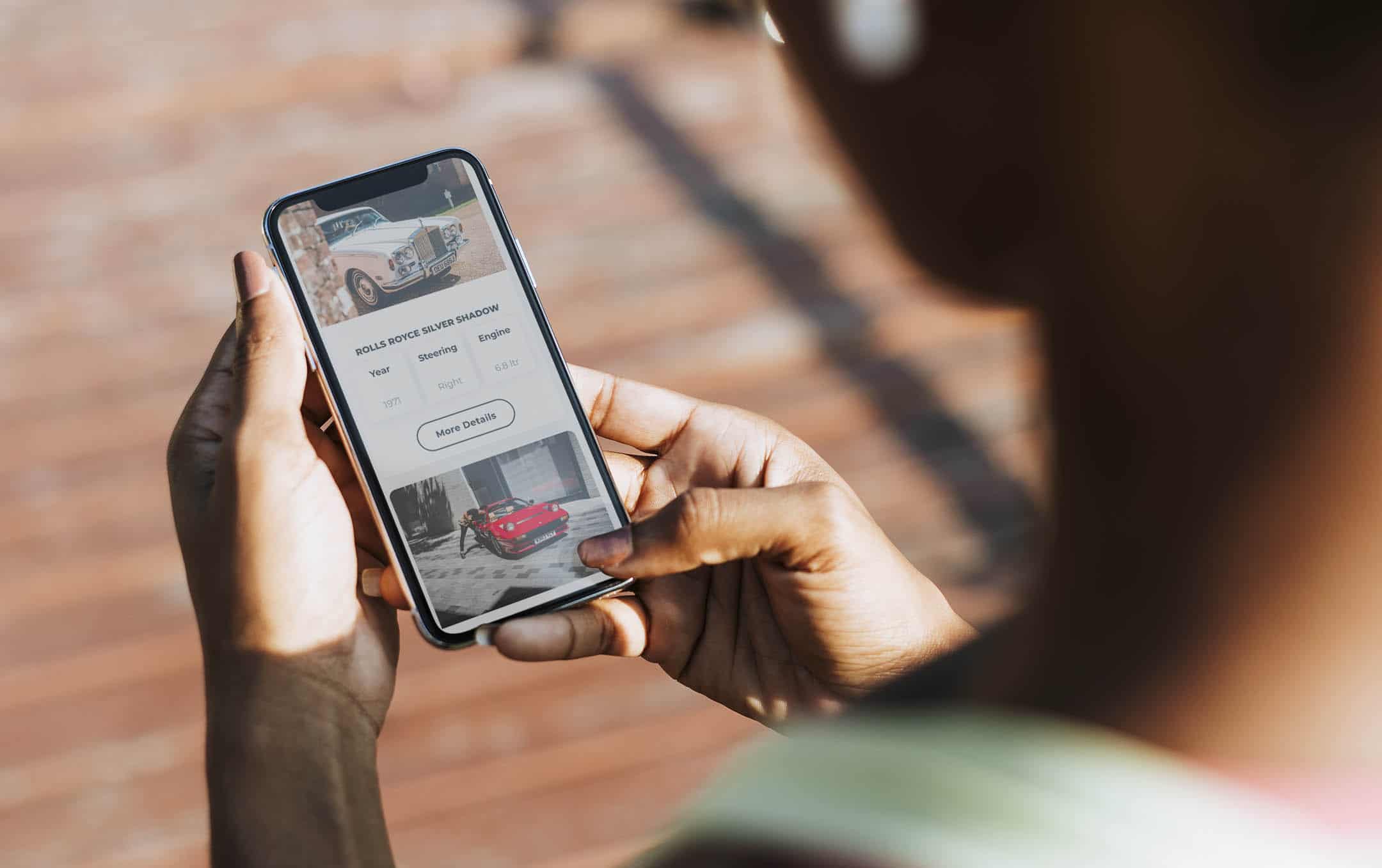 A smartphone user browsing cars on the RNG Classics website